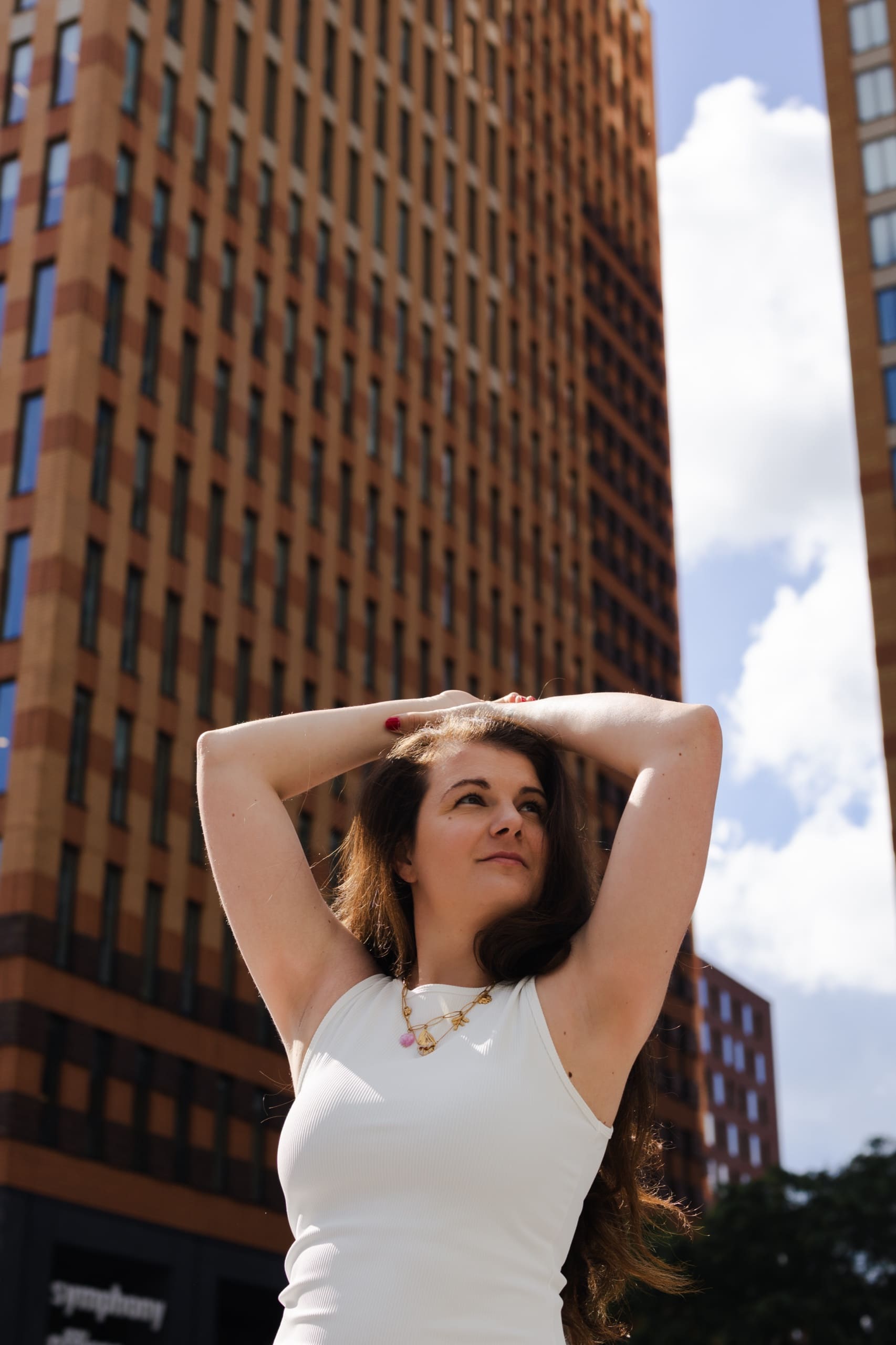 Standing tall among city towers, arms raised, chest open