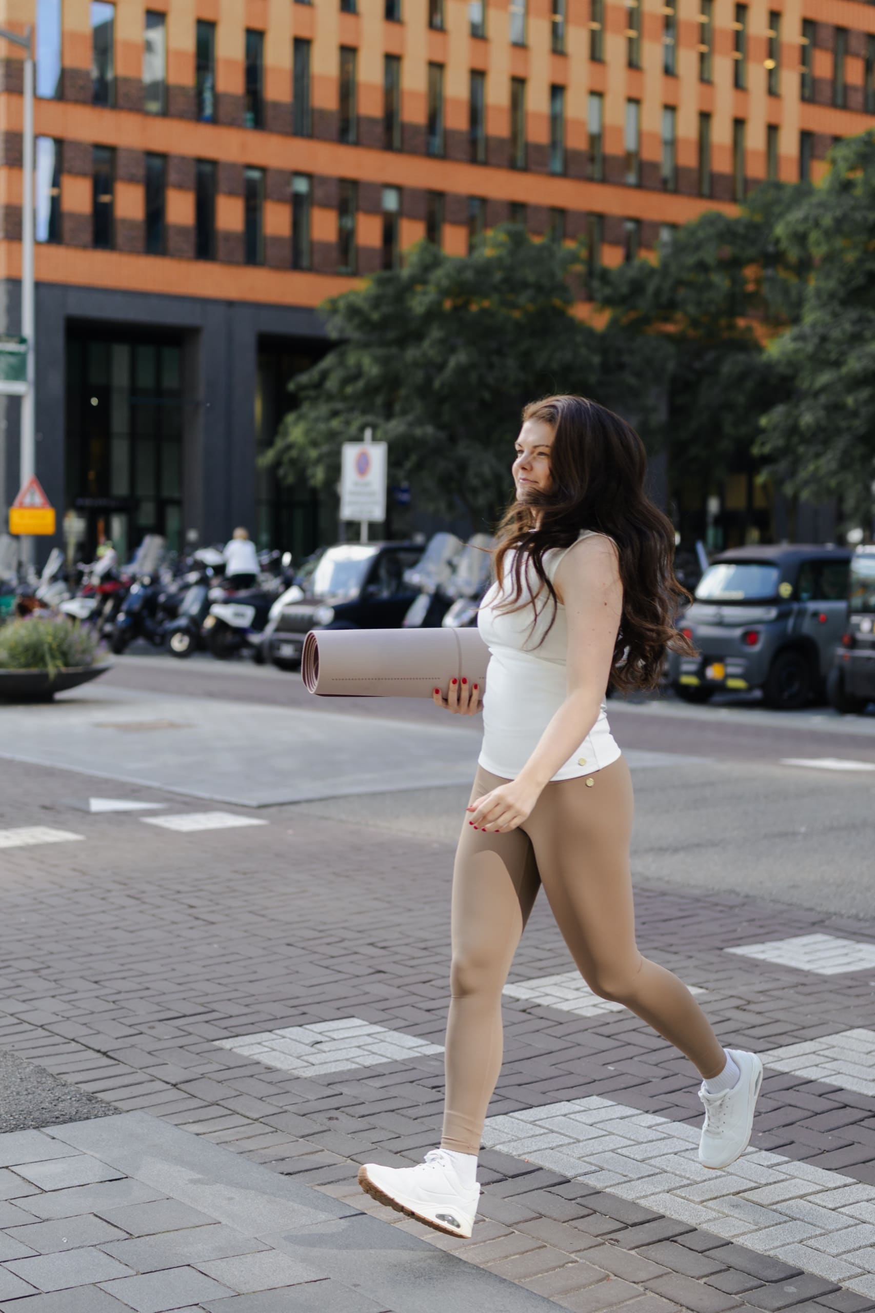 Crossing a city street with a Pilates mat under one arm