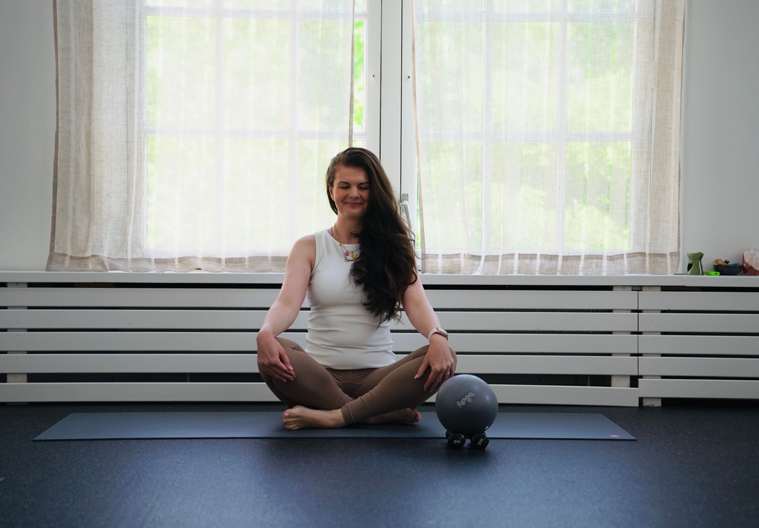 Eszter seated on the mat in the studio, ready to begin